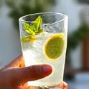 Mujer bebiendo agua fresca en una terraza soleada de Sevilla, con un abanico