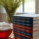 Libros sobre nutrición y meditación apilados junto a una taza de té y gafas de lectura.